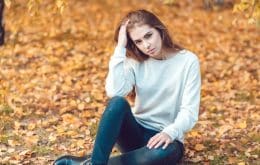 Junge russische Frau sitzt auf Laub im Freien