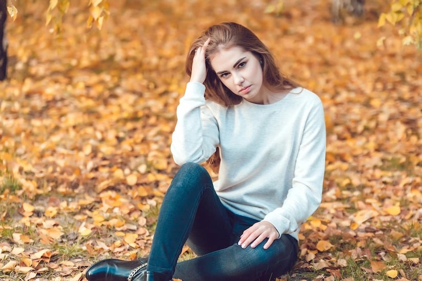 Junge russische Frau sitzt auf Laub im Freien