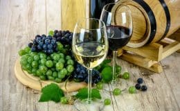 Ist Wein gesund? Ein Weinfass mit 2 Weingläsern und Trauben